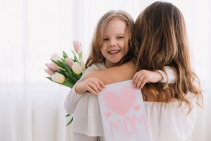 Happy mother's day. child daughter congratulates moms and gives her a postcard and flowers tulips. Premium Photo